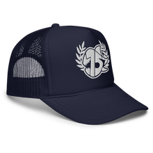 A navy blue trucker hat with white embroidered logo on the front, featuring a laurel wreath and the SEVEN SHARKS logo. The hat has a curved brim and mesh back panels, 