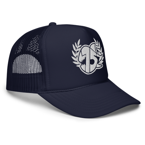 A navy blue trucker hat with white embroidered logo on the front, featuring a laurel wreath and the SEVEN SHARKS logo. The hat has a curved brim and mesh back panels, 